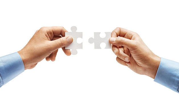 Two men's hands in shirt connecting jigsaw puzzle isolated on white background. Close up. High resolution product