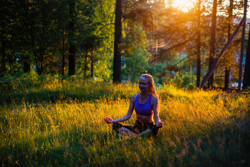 Yoga woman on a picturesque glade in a green forest.