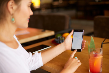 Female scanning fingerprint on her smartphone with program script on laptop display on backround. Woman unlock mobile phone with biometric sensor and finger. Privacy and security concept.