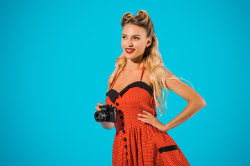 portrait of beautiful smiling woman in retro dress with photo camera isolated on blue