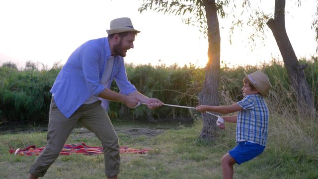 little boy is fooling around with father and playing with bandage outdoors during a family weekend at countryside