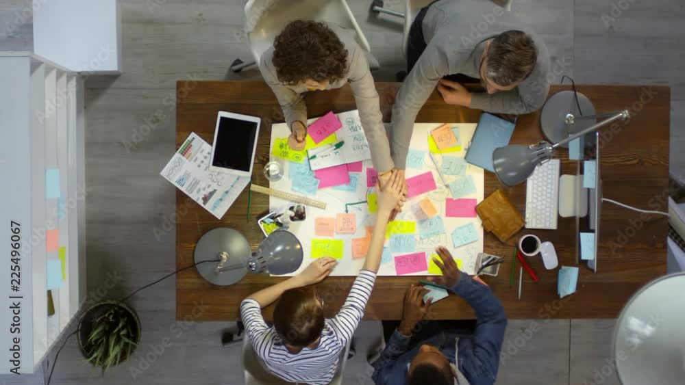 Poster top view of business team making stack of hands after brainstorming ideas with mind maps and sticky 