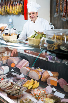 Portrait of  male seller posing with wursts in butchery