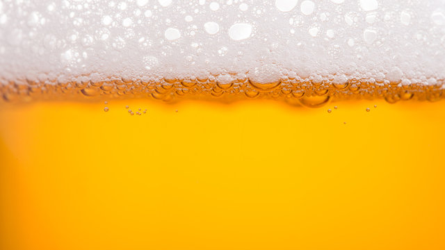 Pouring beer with bubble froth in glass for background. Summer drink, October fest texture