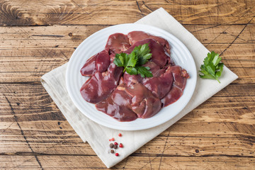 Fresh raw chicken liver on a plate. Wooden rustic background