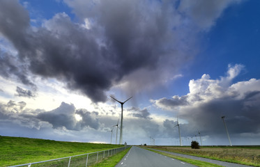 rain and blue sky over wind turbines and road