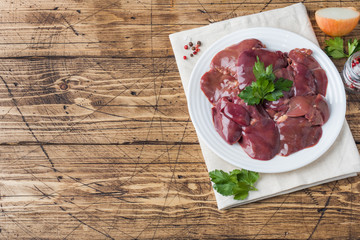 Fresh raw chicken liver on a plate. Wooden rustic background