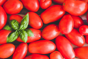 italian homemade flat bread with tomato, feta cheese, ham, and basilic, on  a round cutting board over a black board, flat lay with knife and red wine .