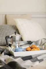 Breakfast in bed. On a white tray there is a coffee maker, coffee blue cup and croissants.