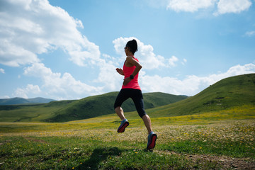 Obraz premium Young fitness woman trail runner running grassland