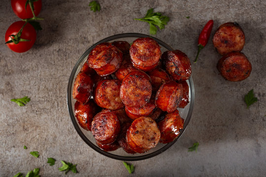 Fototapeta Slices of fried pork sausages with green parsley and cherry tomatoes