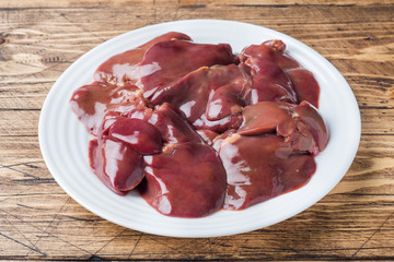 Fresh raw chicken liver on a plate. Wooden rustic background