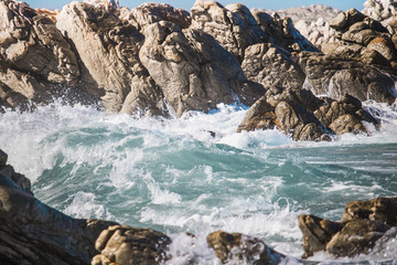 Crashing wave hitting rocks on the shore.