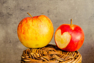 Äpfel mit ausgeschnitzem Herz auf geflechtetem Korb