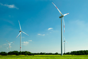 White wind turbines generating electricity in the green farmer's field. Eco power.