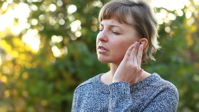 young female having ear pain touching her painful head earache