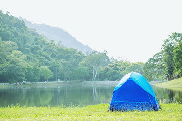 Camping blue tent in forest near lake river in the morning atmosphere refreshing. concept travel.