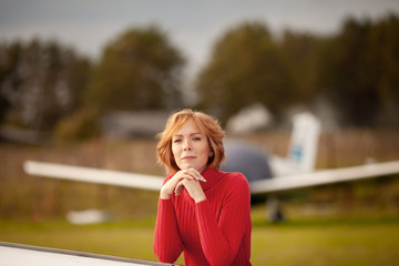 Beautiful girl in red dress and airplane. Walk at airport, autumn,