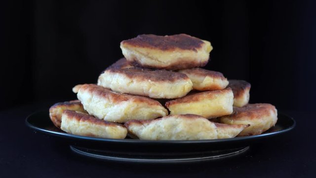 Potato cakes, ukrainian name potato zrazy, stuffed mushrooms or meat or cheese with herbs cream are fried in vegetable oil on black background, close up, rotates. Traditional Ukrainian cuisine