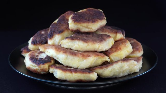 Potato cakes, ukrainian name potato zrazy, stuffed mushrooms or meat or cheese with herbs cream are fried in vegetable oil on black background, close up, rotates. Traditional Ukrainian cuisine