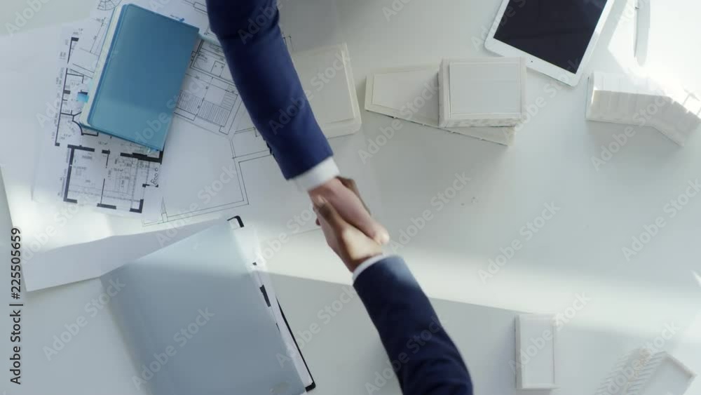 Poster top view of two unrecognizable male entrepreneurs of different ethnicities shaking hands after reach