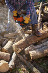 The worker works with a chainsaw. Chainsaw close up. Woodcutter saws tree with chainsaw on sawmill. Chainsaw in action cutting wood. Man cutting wood with saw, dust and movements.