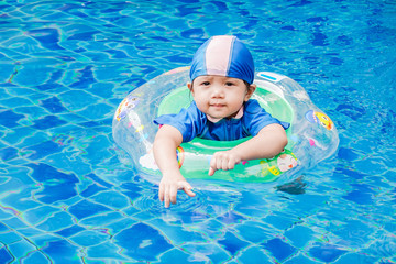 One little girls swimming in the pool with rubber ring, having fun in swimming pool.