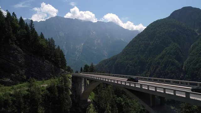 Aerial - Landscape shot with cars driving over concrete bridge in the mountains