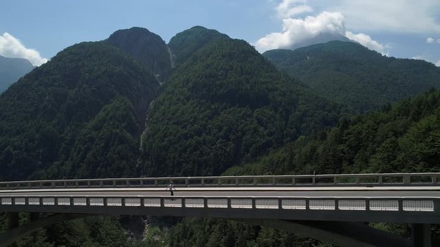 Aerial - Extreme long tracking shot of longboarder pushing across the viaduct