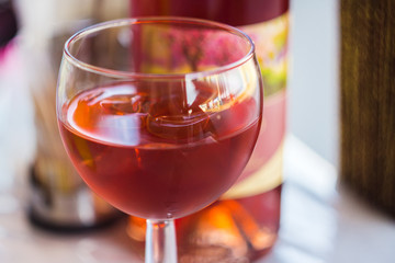 glass of rose wine on wine bottle background, soft focus