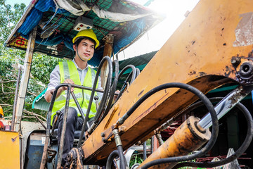 Portrait of a male developer sitting operator driving excavator at construction site.