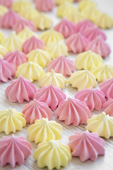 Mini meringues on a white wooden surface, side view. Selective focus.