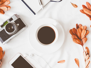 top view of coffee shop concept with coffee cup, notebook, dry leaf, retro camera and smartphone on...
