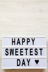 Modern board with text 'Happy Sweetest Day' word over white wooden surface, top view. From above, flat lay, overhead. Copy space.