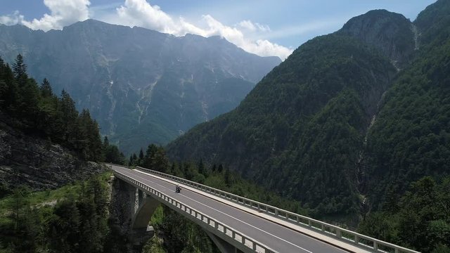 Aerial - Motorcycles driving across the concrete bridge on mountain pass
