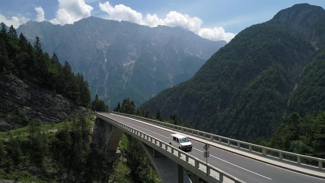 Aerial - White van driving across the mountain viaduct in spring