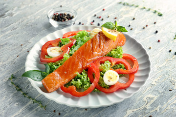 Plate with tasty salmon and salad on light table