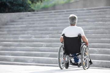 Senior man in wheelchair near stairs outdoors