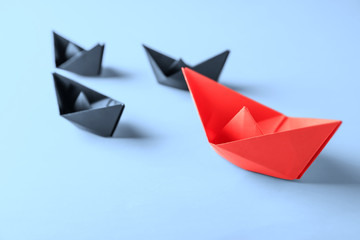 Origami boats on light background. Leadership concept