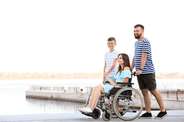 Young woman in wheelchair with her family walking outdoors