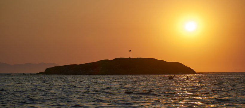 Kayaking. Sunset On The Turkish Coast Of The Aegean Sea. View Of The Island. Orange Sky And Blue Sea.