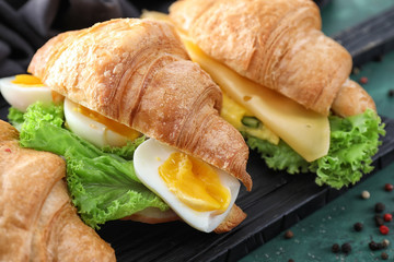 Tasty croissant sandwiches on wooden board