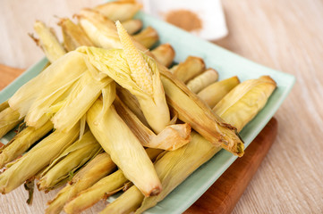 Delicious homemade izakaya-like roast baby corn in wooden background, Taiwan delicacies, top view, copy space