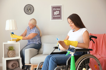 Young woman in wheelchair and her mother cleaning home