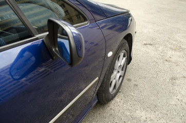 Close up view with automobile. Front car wheel on the asphalt road and rearview mirror. Tyre, tire.