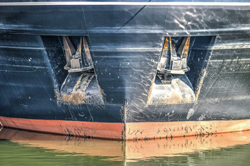 Front view of a ship's bow, with two large anchors placed in square cavities in the hull
