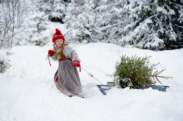 Little girl finding christmas tree in the forest in deep snow