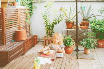 female child outdoor sitting table having breakfast - morning routine, eating, hunger concept