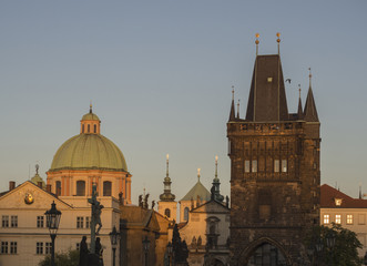 View from Charles Bridge on Mala Strana bridge tower with churches and pallace of old Prague at sunset golden hour light