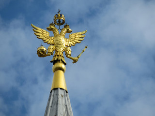 Coat of arms of Russia on blue sky with clouds. Golden Imperial eagle, Russian state emblem on top of the tower on Red square in Moscow